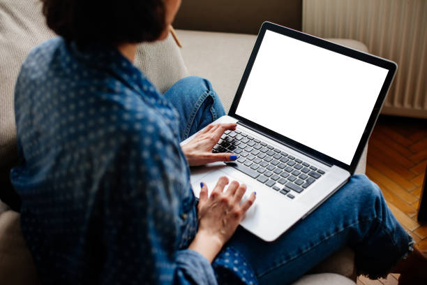 image recadrée de femme à l'aide d'ordinateur portable avec écran blanc - regarder par dessus son épaule photos et images de collection