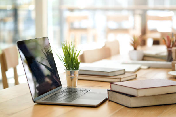 Desk with laptop, books and business office background.