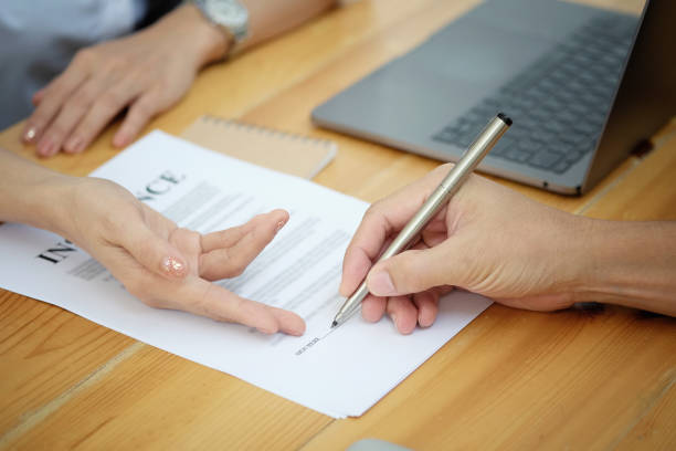 istock Man signing a car insurance policy, the agent is pointing the document 964772092