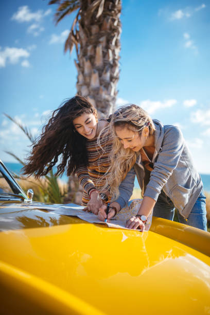 istock Young women on road trip reading map for route planning 964774744