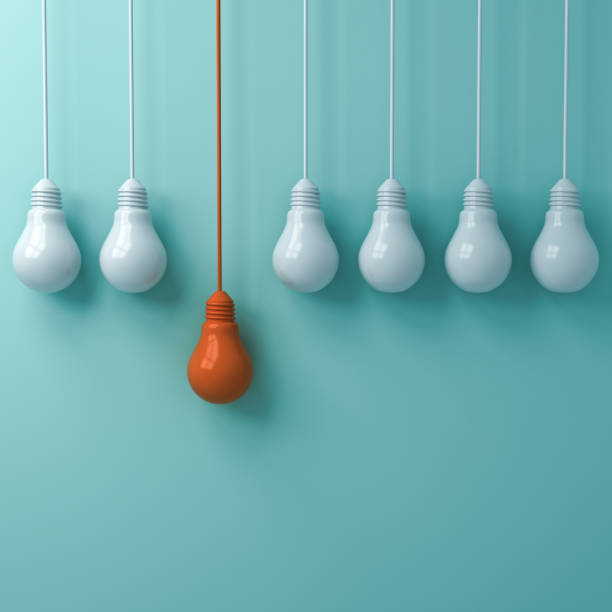 istock Think different concept , One hanging orange light bulb standing out from the white light bulbs on green pastel wall background , leadership and individuality creative idea concepts 3D rendering 964774830