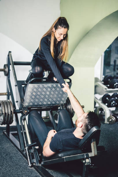 istock Young handsome man with his girlfriend exercise legs in the gym. 964778232