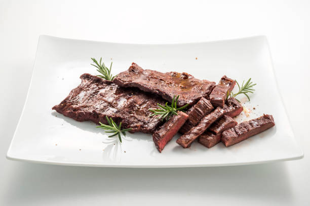Meat dish Skirt Steak Square white plate of sliced skirt steak and rosemary flank steak stock pictures, royalty-free photos & images