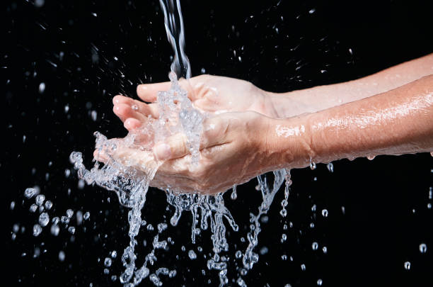 istock Hands being rinsed under running water against black 964789790