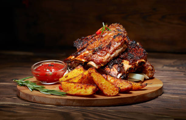 côtes de fried avec romarin, rustiques de pommes de terre, oignon, sauce sur planche de bois rond. fond sombre. place pour le texte, fond - travers de porc photos et images de collection