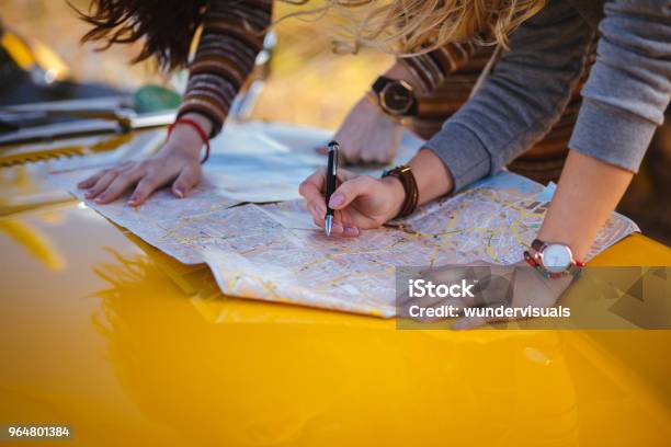 Women On Summer Road Trip Reading Map For Directions Stock Photo - Download Image Now