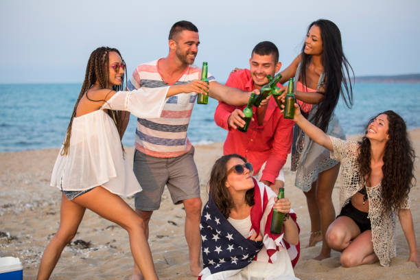 istock Young people drinking beer and celebrating on beach 964804778