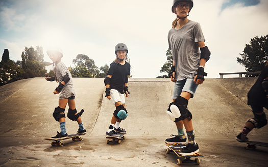 Shot of a group of young girls skateboarding together at a skatepark