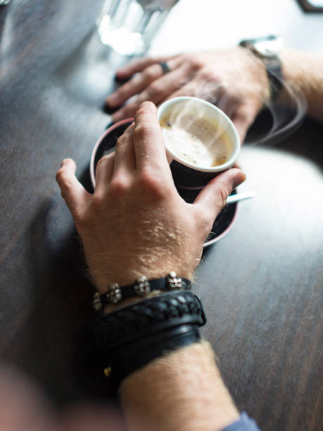 hipster's hands with a cup of coffee in the cafe at the table, close-up