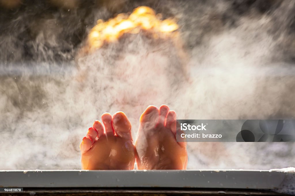 Woman holds her feet up while in a hot tub Woman holds her feet up while in a hot tub with steam Bathtub Stock Photo