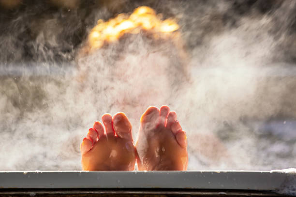 Woman holds her feet up while in a hot tub Woman holds her feet up while in a hot tub with steam hot spring photos stock pictures, royalty-free photos & images
