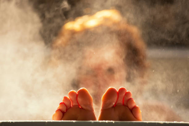 Woman holds her feet up while in a hot tub with steam