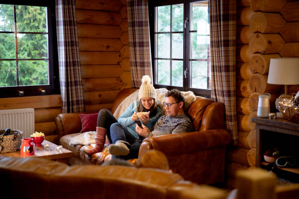 Relaxing on the Sofa A man uses a smartphone whilst his wife watches. The woman is holding a hot drink and they are both sitting on the sofa. food recall stock pictures, royalty-free photos & images