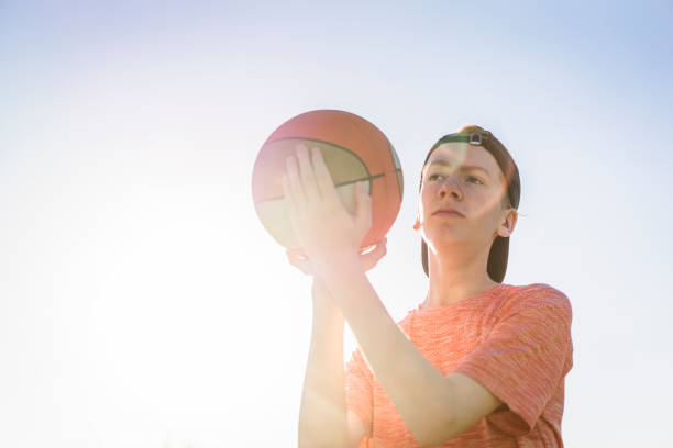 istock Boy throwing basketball against sky 964827948