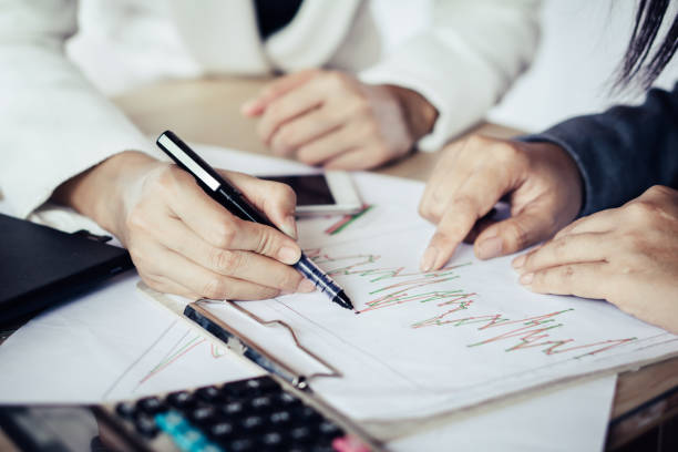 istock two Asian business woman talking and working together at office analyzing on financial graph 964828256