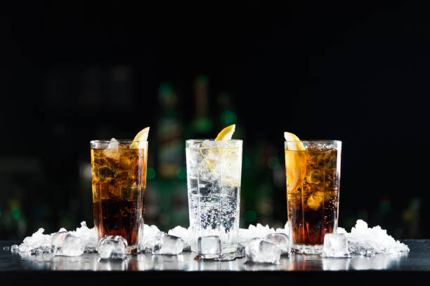 dos whisky y coca-cola cócteles y una bebida alcohólica blanca en la barra de tabla. - cola gaseosa fotografías e imágenes de stock