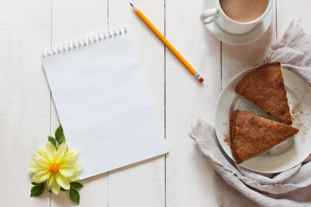 Notebook with a pencil and pie on wooden background