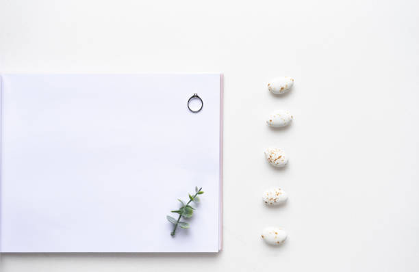 istock Wedding wish book, rings, candy and oregano branches on white marble. Top view 964832238