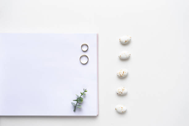 istock Wedding wish book, rings, candy and oregano branches on white marble. Top view 964832470