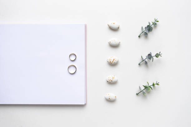 istock Wedding wish book, rings, candy and oregano branches on white marble. Top view 964833152