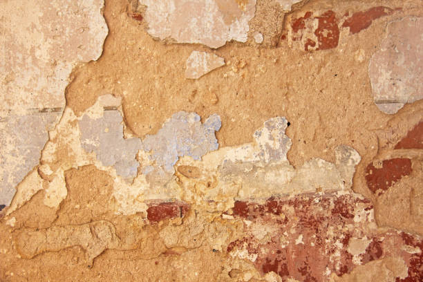 istock Old flaky white paint peeling off a grungy cracked wall. Cracks, scrapes, peeling old paint and plaster on background of old cement wall. An old cement stone wall as vintage cracked. Brick wall. 964835050