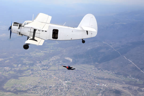 istock Parachutists jump from a vintage biplane 964842130
