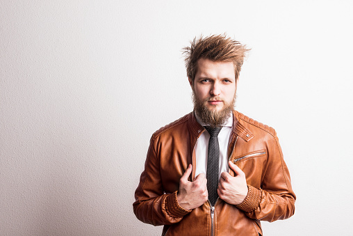 Portrait of a young handsome hipster man in a studio on a white background. Copy space.