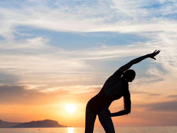 istock young girl practicing yoga on the beach during the sunset 964843040
