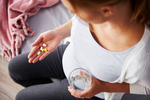 Young pregnant woman taking medicine Young pregnant woman taking medicine folic acid stock pictures, royalty-free photos & images