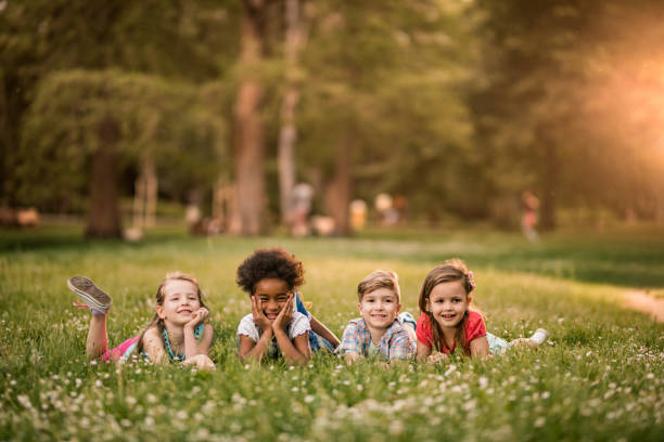 istock Happy children enjoying in spring day while lying in grass and looking away. 964843260