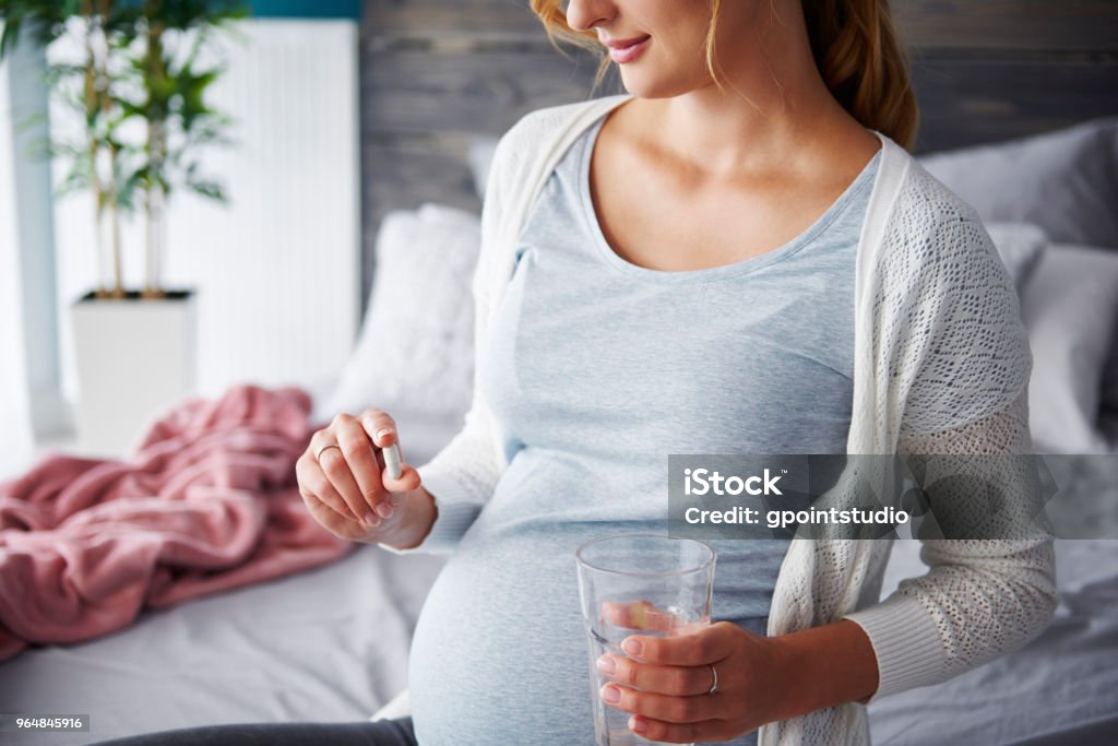 Young pregnant woman taking capsule Pregnant Stock Photo