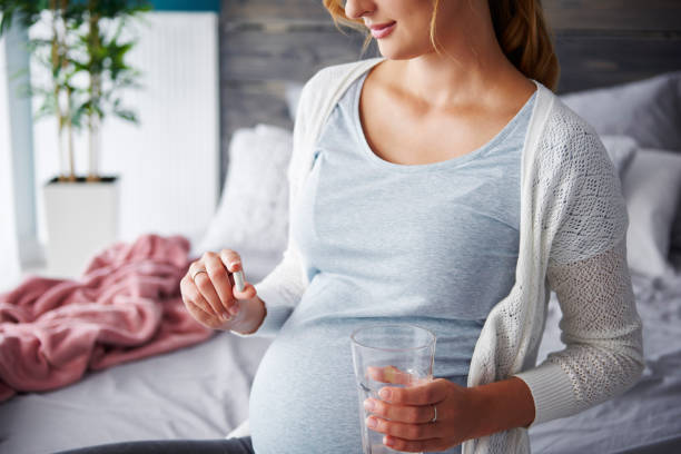 Young pregnant woman taking capsule Young pregnant woman taking capsule folic acid stock pictures, royalty-free photos & images