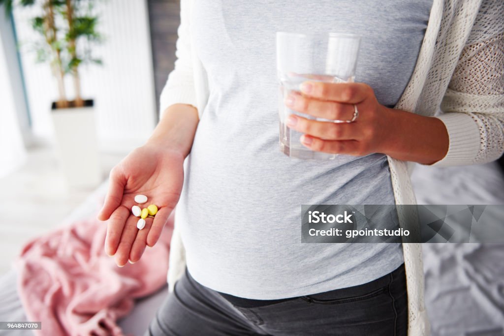 Mujer embarazada teniendo medicamentos - Foto de stock de Embarazada libre de derechos