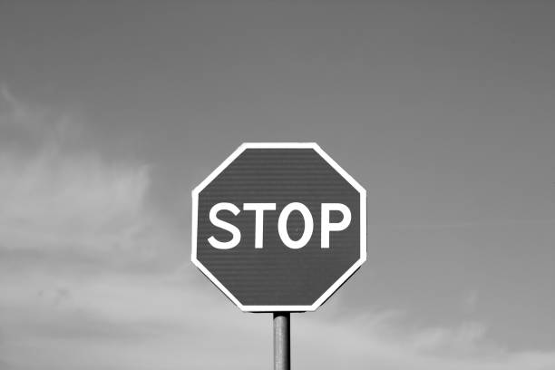 istock Stop sign against cloudy sky in black and white. 964851594