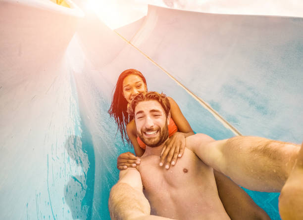 Happy crazy couple taking selfie photo with action camera in aqua park - Young people having fun in summer holidays with technology trends - Vacation, youth, love and travel concept - Focus on faces feliz pareja loco tomando selfie foto con la cámara de acción en parque acuático - jóvenes de personas que se divierten en vacaciones de verano con tendencias tecnológicas - vacaciones, juventud, amor y viajes concepto - centrarse en las caras