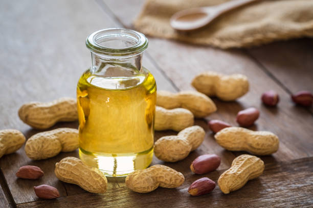 peanut oil in glass bottle and peanuts on wooden table - arachis hypogaea fotos imagens e fotografias de stock