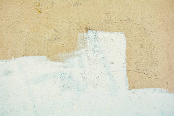 istock Yellow rough concrete wall with cracks and white paint 964879994