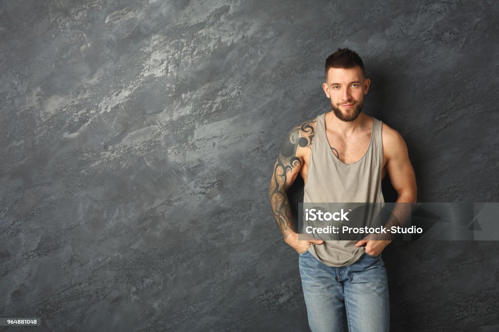 英俊的微笑紋身男子擺在演播室 - 免版稅男人圖庫照片