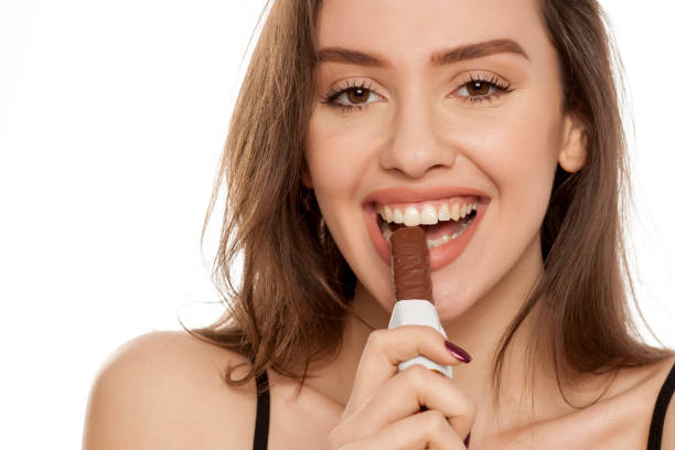 istock young happy woman enjoying eating chocolate on a white background 964883576