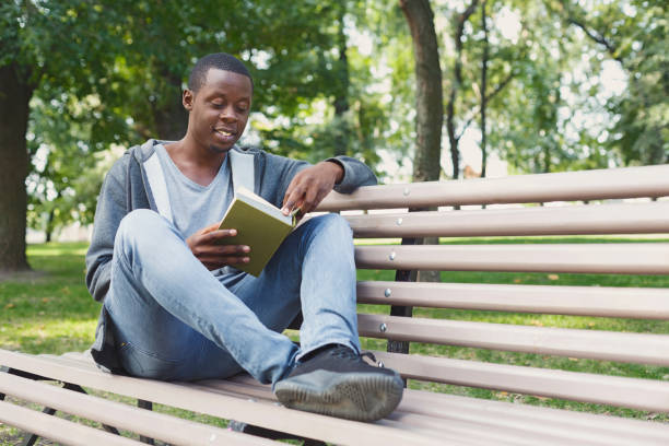 istock Young man reading book in park copy space 964887552