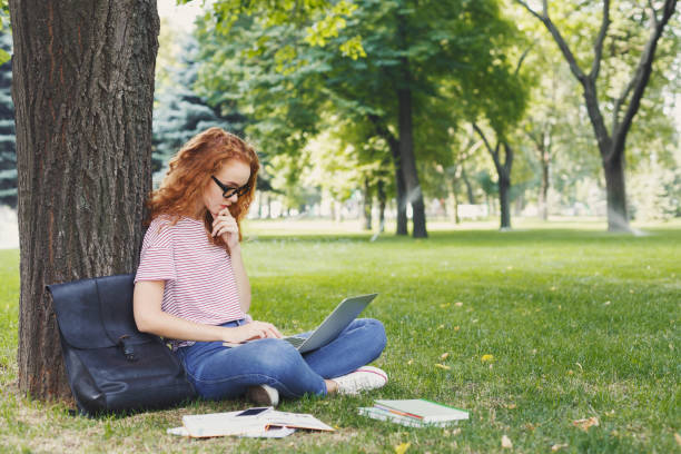 Attractive student with laptop and notebook outdoors