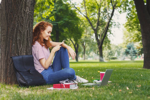 istock Happy young woman texting on smartphone in park 964890624