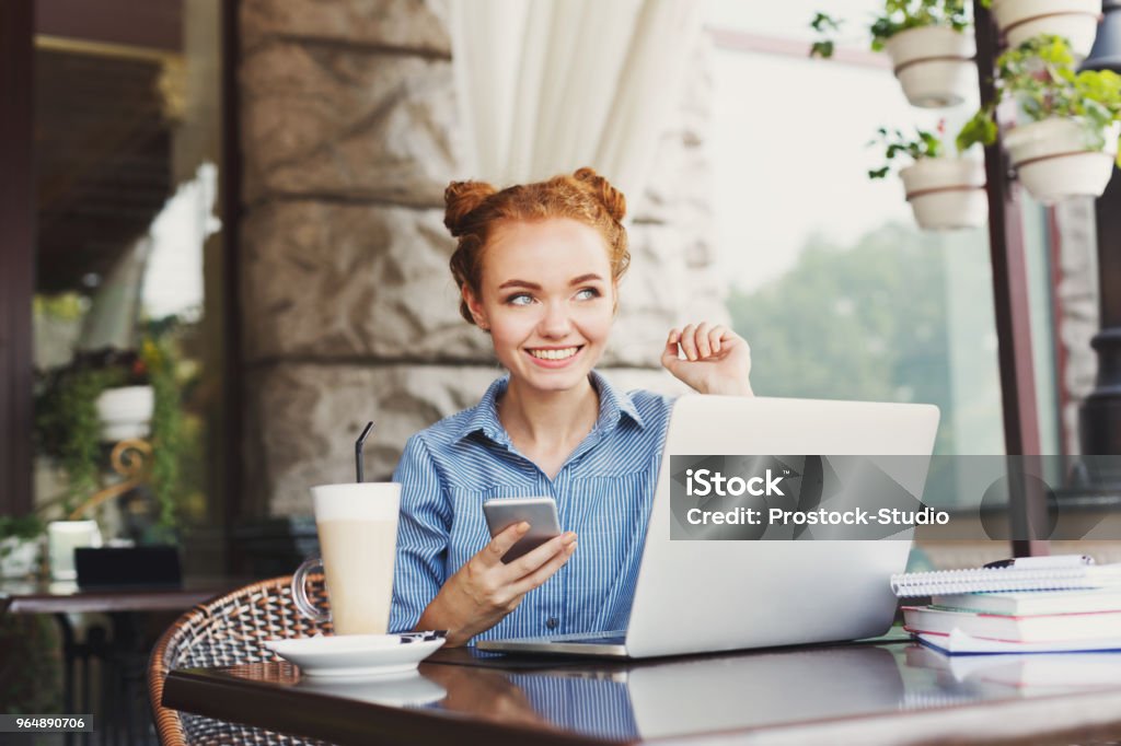 Nuori punatukkainen nainen tekstaa puhelimessa - Rojaltivapaa avainsanalla Aikuinen ja tyyppiä Kuvapankin valokuva