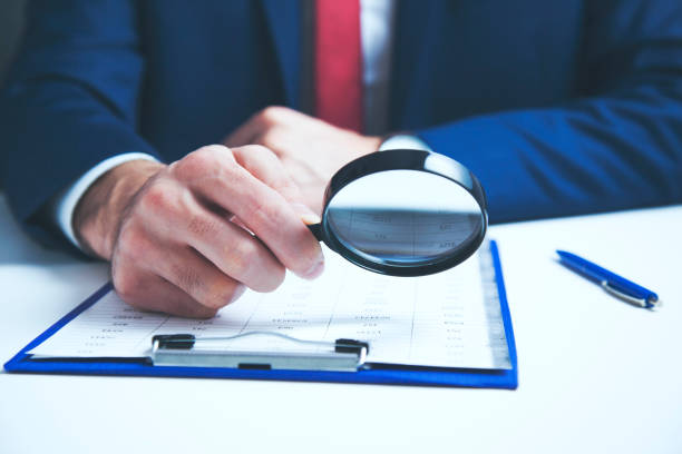 istock Businessman checking a document with a magnifying glass 964895388