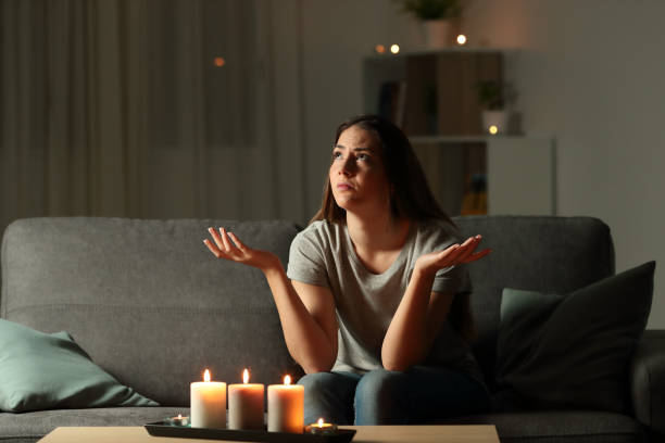 Woman complaining during a blackout at home Woman complaining during a blackout sitting on a couch in the living room at home blackout photos stock pictures, royalty-free photos & images