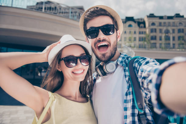 pareja alegre moda positiva en mayúsculas que viaje, viaje, reunión al aire libre tiro autorretrato en cámara frontal, día soleado sol, hombre guapo mujer hermosa con la cerda, ropa casual - people personal accessory town hat fotografías e imágenes de stock