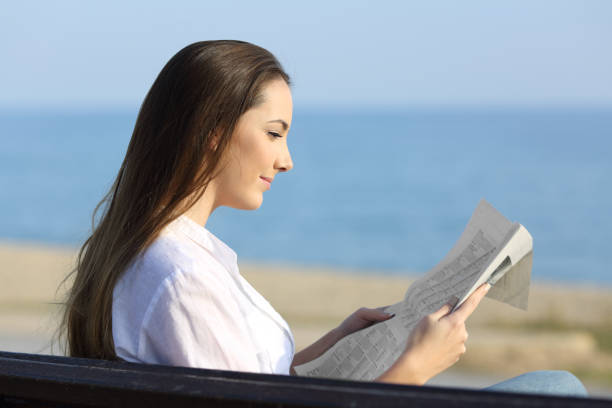 Woman reading a newspaper outside on the beach