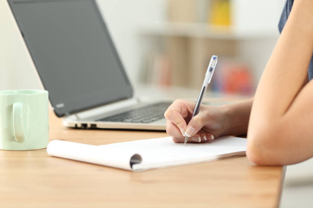 istock Female hand writing notes in a notebook on a desk 964912254