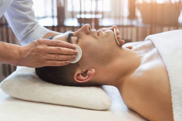 homme d’obtenir un traitement du visage au salon de beauté - massaging men beauty spa beauty treatment photos et images de collection