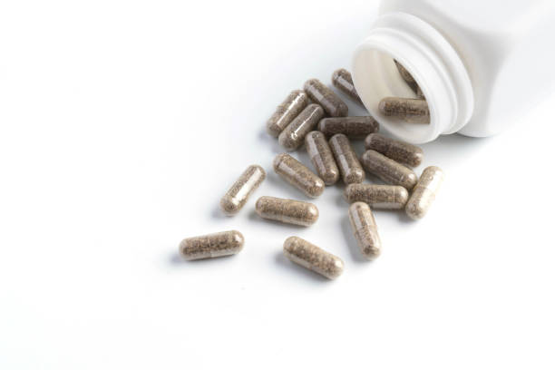 istock herb capsules spilling out of a bottle on white background 964915142
